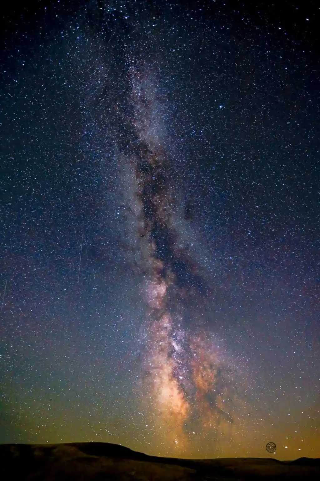 The Milky Way rising vertically over dark canyon hills